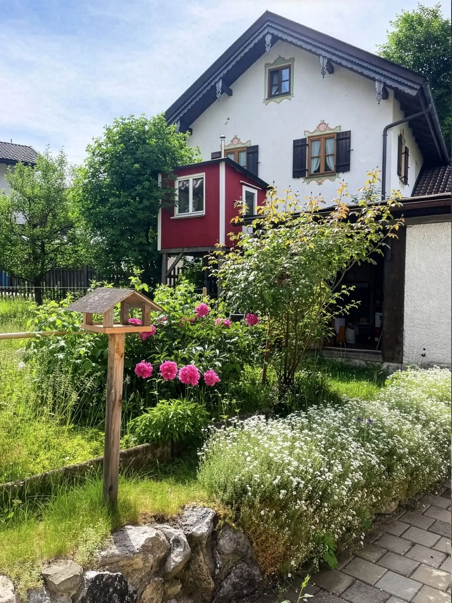 Garten mit Blumen, Vogelhaus und dem roten Baumhaus