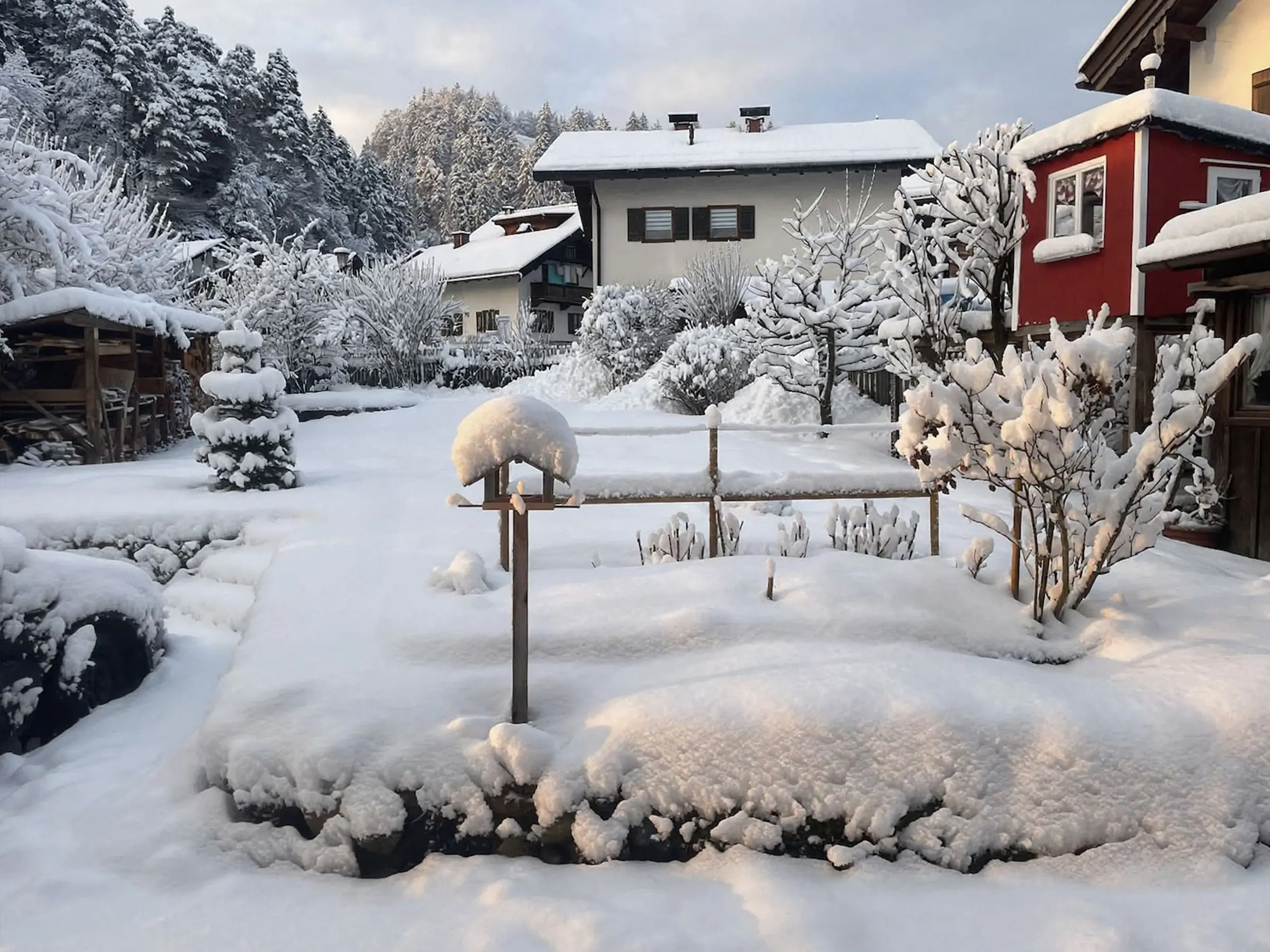 Verschneiter Garten des Ferienhauses mit Blick auf die Berge