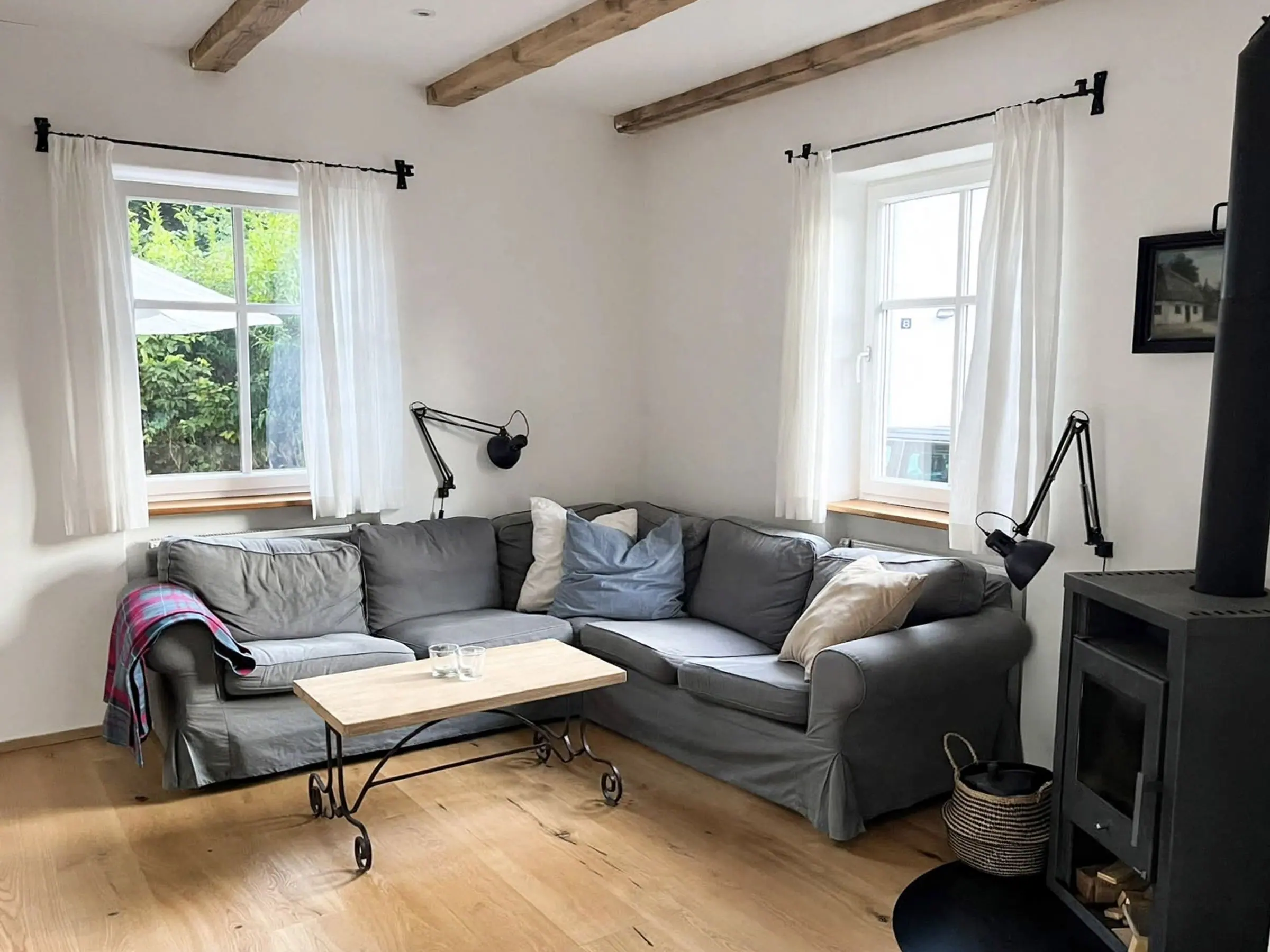 Wohnzimmer mit Ecksofa, Holzboden und Kaminofen