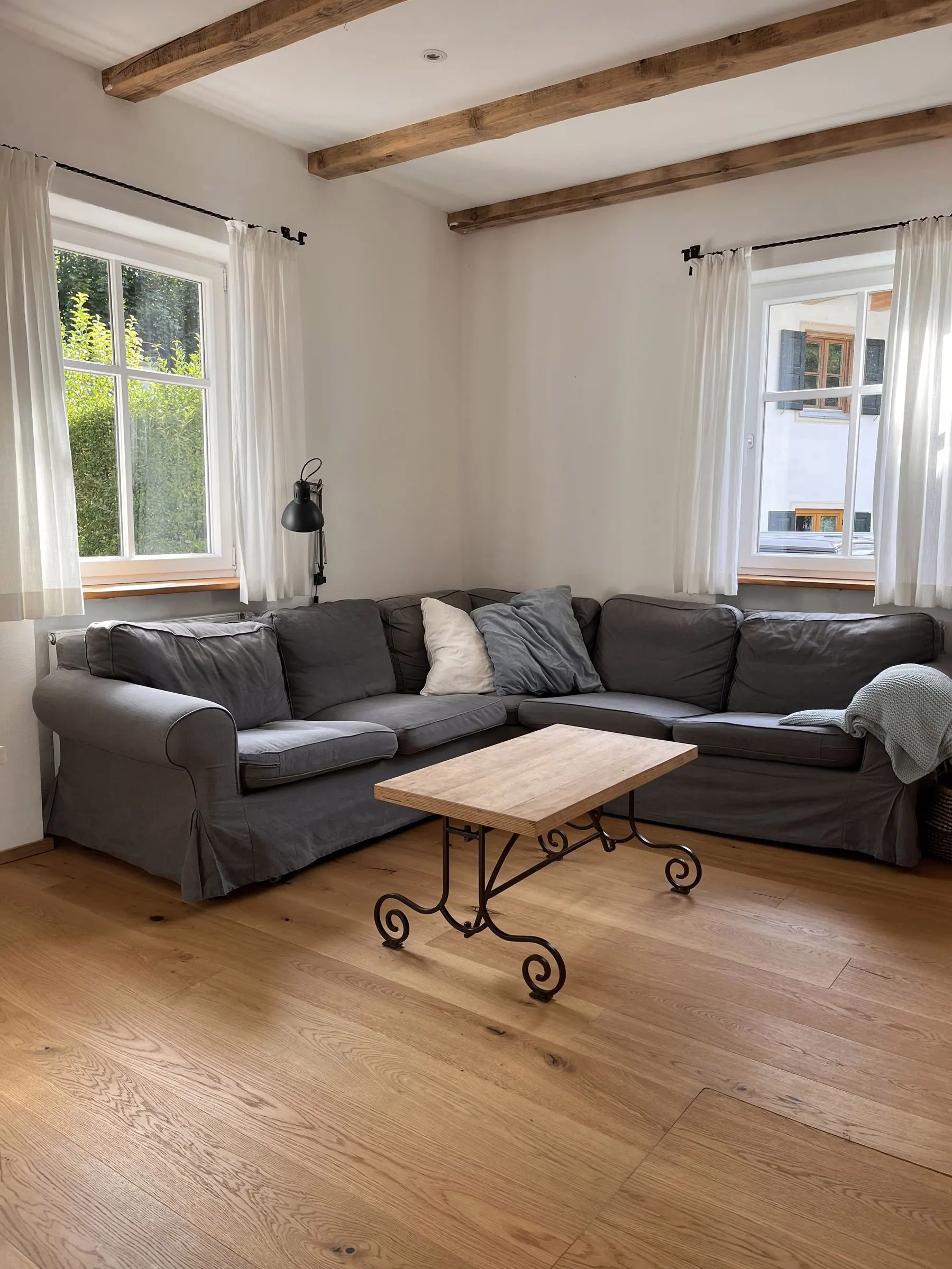 Ecksofa mit Couchtisch vor zwei Fenstern